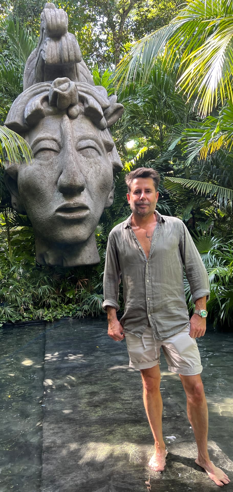 Toni, de Exotik Mayan Tours, junto a una escultura maya rodeada de vegetación